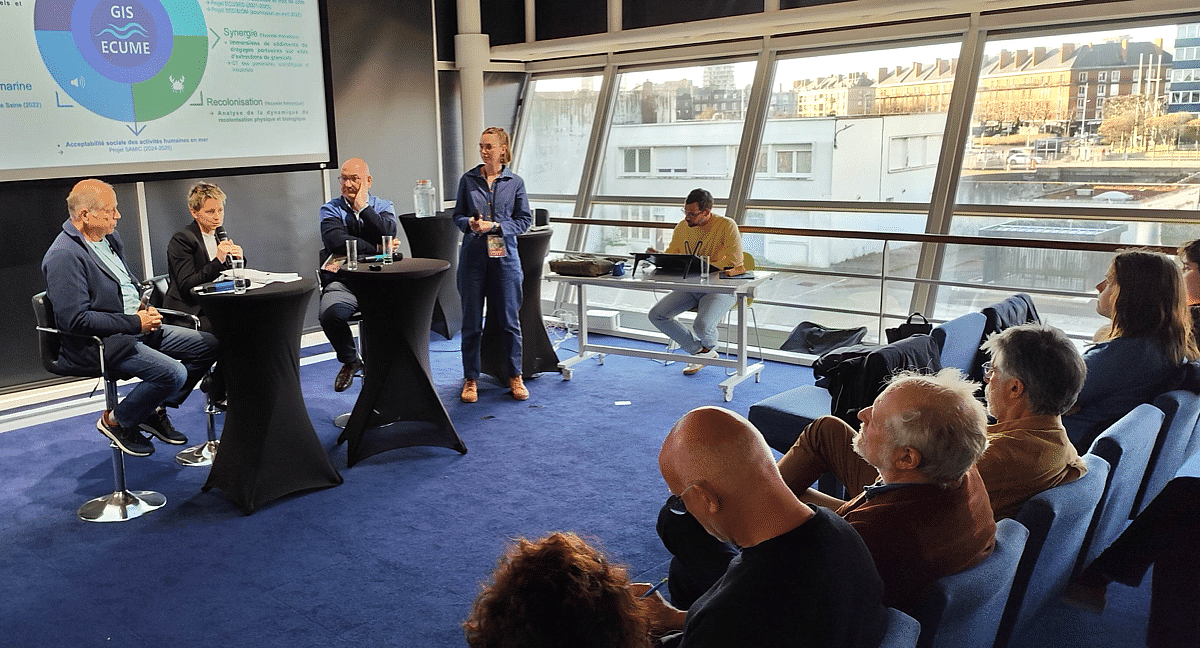 Des intervenants face à un public dans une salle de conférence